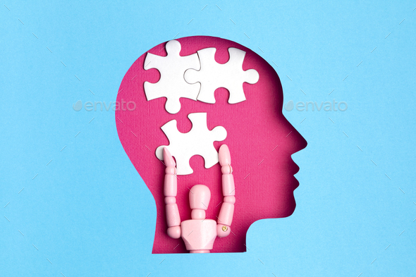 Papercut head with jigsaw puzzle pieces inside. Mental health problems, psychology, memory, logic
