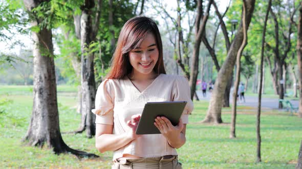 Asian woman using digital tablet park, Lifestyle and Holiday of family time.