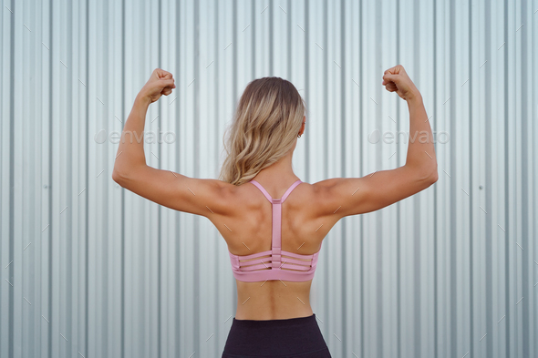 A women body builder flexing on a pink back ground. - Stock