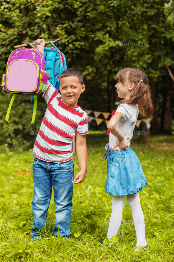 A strong child picks up two backpacks. Boy and girl Back to school.