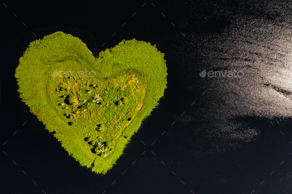 Love island on a lake in Europe, a Green heart-shaped Island on a dark lake with a sparkle from the