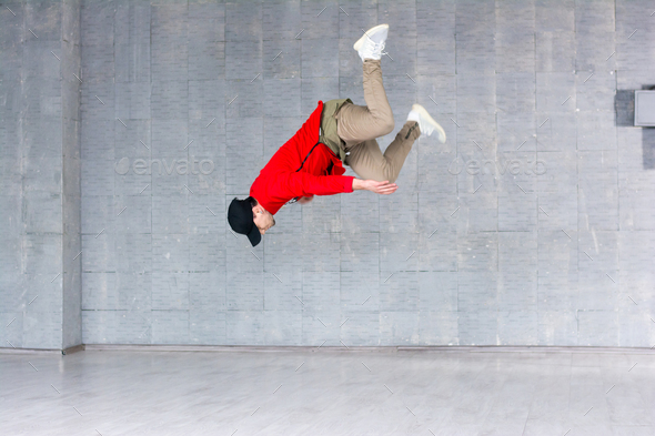Rap dancer jumping on grey background.