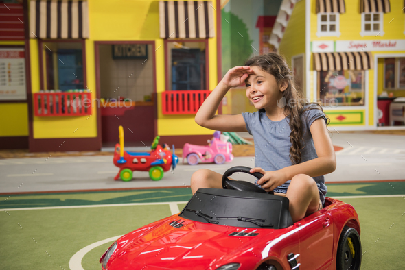 Girl playing with toy car in game center. - Stock Photo - Images