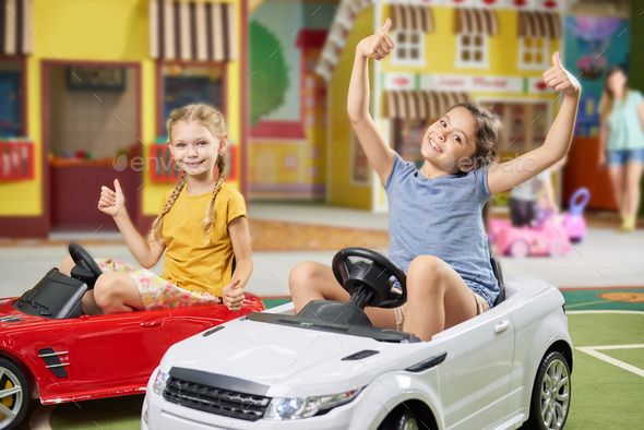 Two funny girls playing with electric toy car. Stock Photo by ...