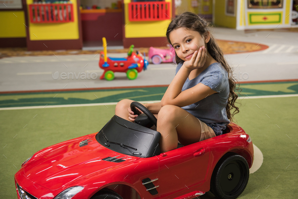 Cute child sitting in toy car at game room. - Stock Photo - Images