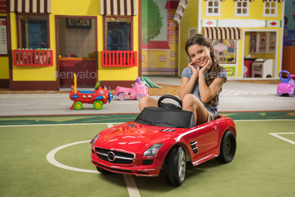 Pretty little girl with mini car at game center. - Stock Photo - Images