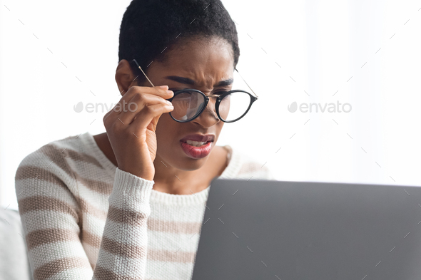 Poor Eyesight Concept. African American Lady In Eyeglasses Looking At Laptop Screen