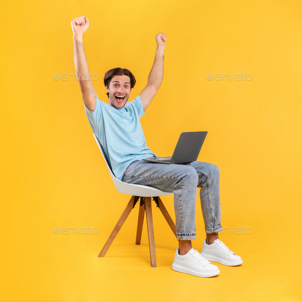 Excited guy using laptop celebrating success shaking fists