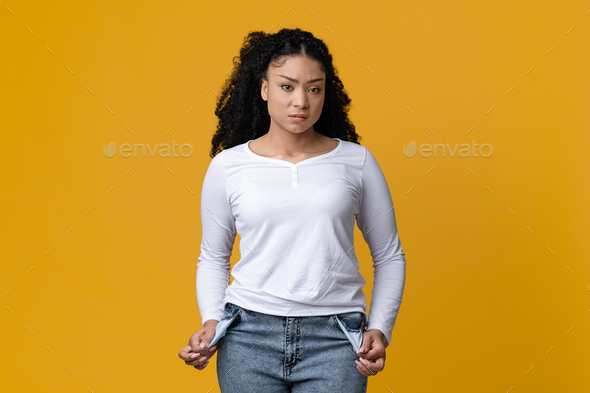 Poverty Concept. Portrait Of Upset Young Black Woman Showing Her Empty Pockets