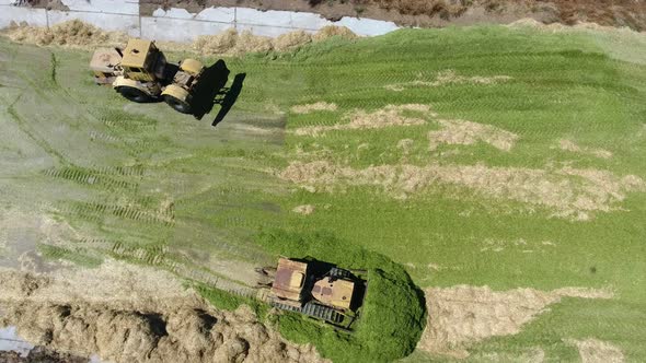 Aerial Shot of Two Bulldozers Moving on a Silo Storage on a Sunny Day in Summer