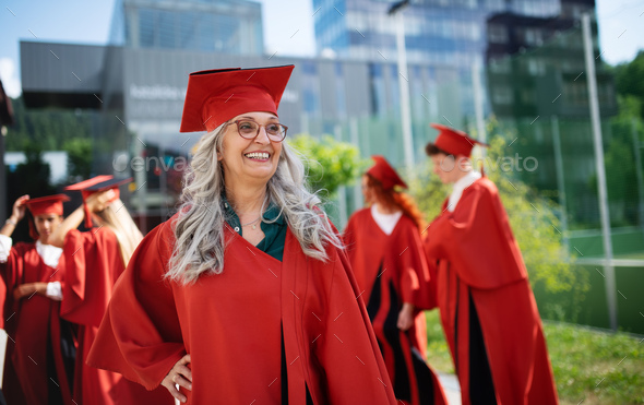 Portrait of cheerful senior woman student outdoors, graduation and third age university concept