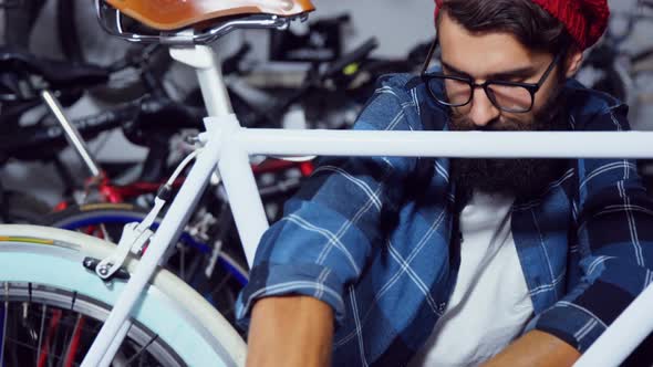 Portrait of mechanic repairing a bicycle in workshop alt