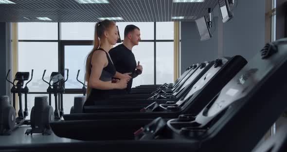 A Man And A Girl Go In For Sports In The Gym. Running On A Treadmill  alt
