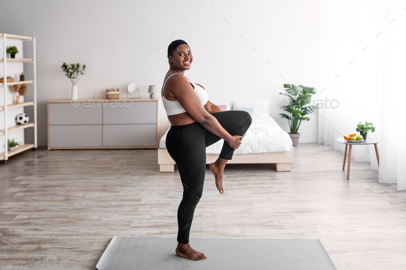 Overweight black lady stretching leg, making flexibility exercises