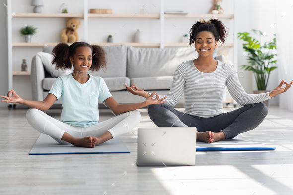 Cheerful black mom and daughter having online yoga class Stock Photo by  Prostock-studio