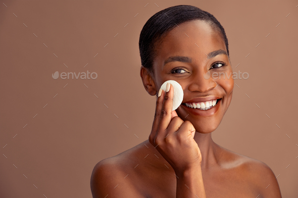 Black beautiful woman using cotton pad to remove make up
