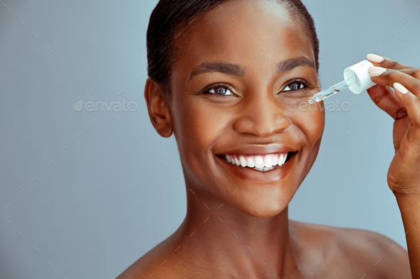 Black beauty woman dropping collagen serum moisturizer on face - Stock Photo - Images