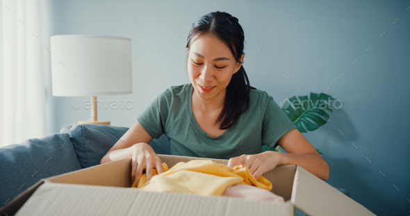 Happy asia lady open cardboard box package exciting and enjoy trying and matching.