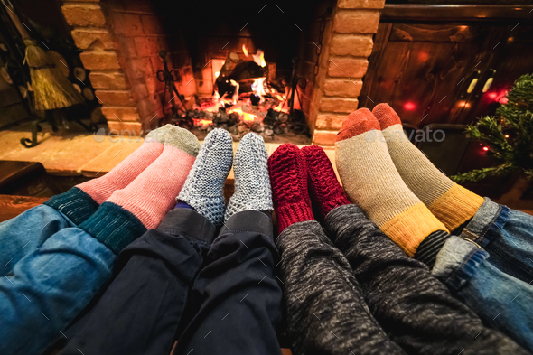 Legs view of happy family wearing warm socks in front of fireplace