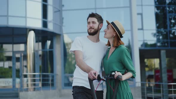 Young Couple in Love Having Fun When Talking on a Walk with Electro Scooters alt