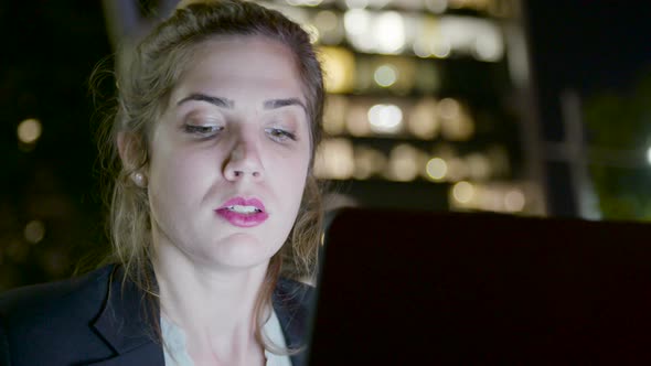 Young business woman sitting in a cafe at night, working on a laptop computer alt