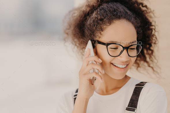 Cheerful woman with crisp hair, satisfied with tariffs for telephone call - Stock Photo - Images