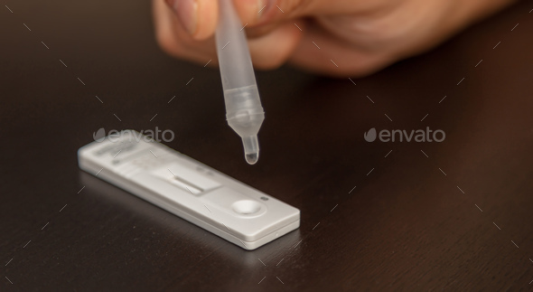 Man performing a self test. Rapid antigen diagnostic test kit with nasal swab and tube.