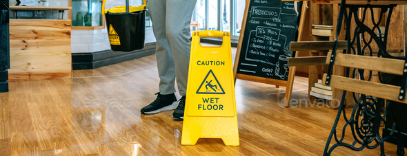 Worker placing wet floor sign after mopping
