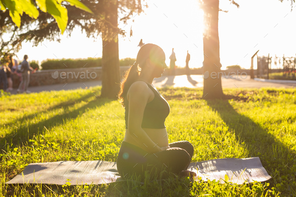 Peaceful young positive pregnant woman in gymnastic suit does yoga