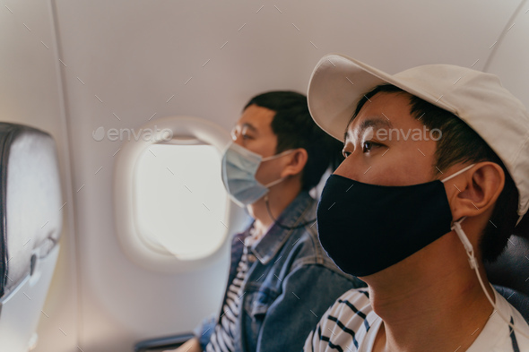 Asian male tourists wearing a face mask inside aircraft cabin air