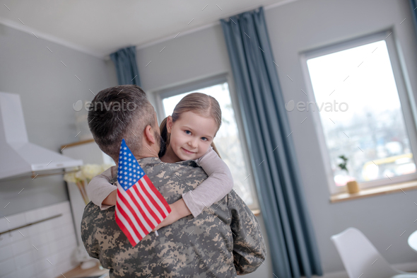Little girl with the American flag on the hands of officer.