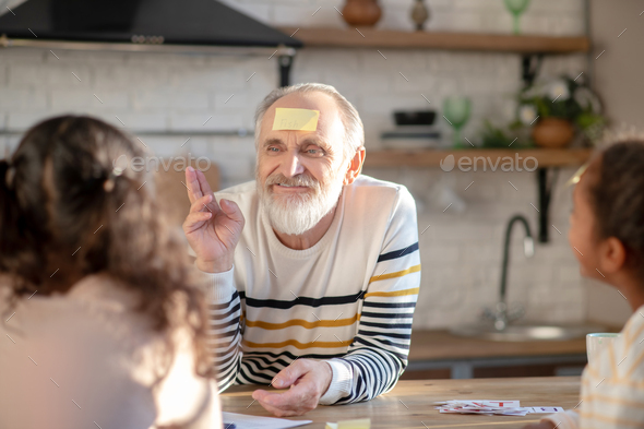 Grey-haired man playing guess game with his granddaughters