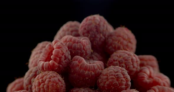 Ripe Raspberry Berries Piled on A Plate, Rotated Against a Black Background