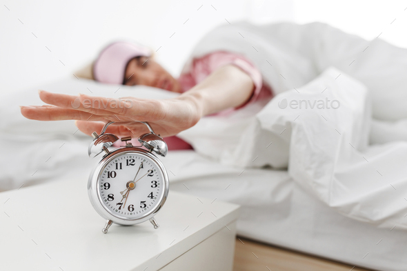 Alarm clock ringing, woman waking up in early morning for work, sleeping disorder
