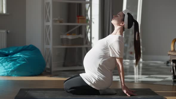 Wide Shot Pregnant Young Yogi Exercising Sitting Indoors at Home Breathing alt