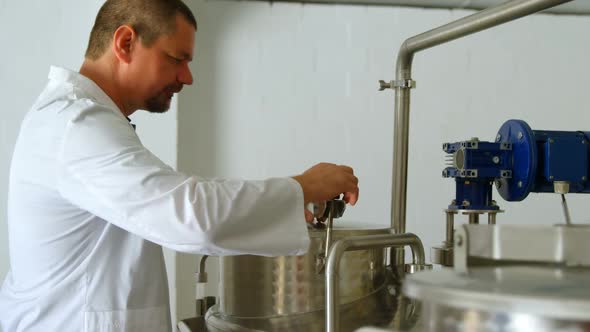 Male worker checking distillation tank in factory alt