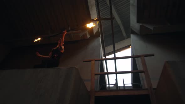 Young Guy with Burning Staff Doing Fire Show on Concrete Background Under Road
