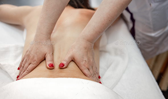 Female hands do a back massage to a man in the salon. Stock Photo by puhimec