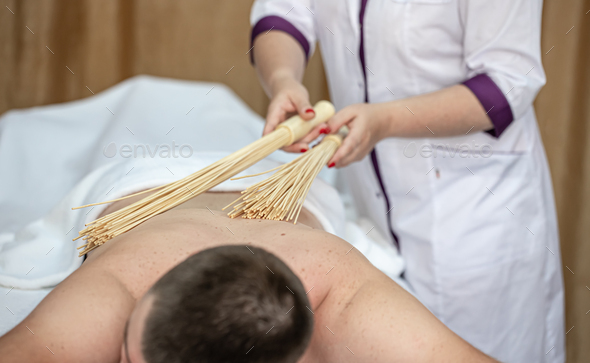 Female hands do a back massage to a man in the salon. Stock Photo by puhimec