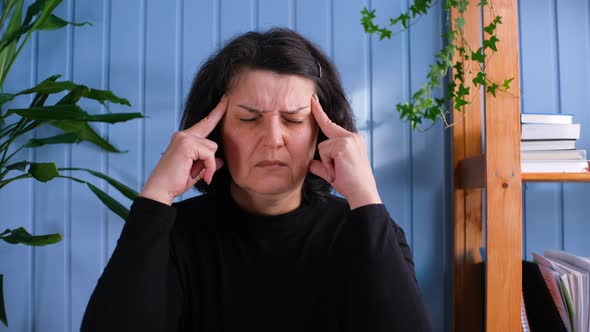 Middleaged Woman with a Headache Sitting in Home and Feel Ill Unhappy