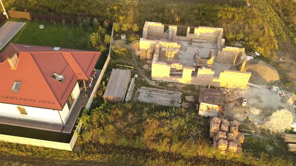 Top down aerial view of two private houses, one under construction with wooden roofing frame alt