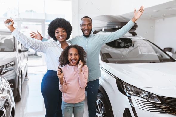 Excited Afro family showing key, shouting WOW, feeling happy over buying new auto, raising hands up