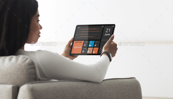 Black woman holding digital tablet with smart home app