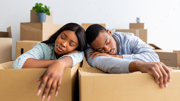 African american family sleeping on unpacked carton boxes, exhausted after moving to new house