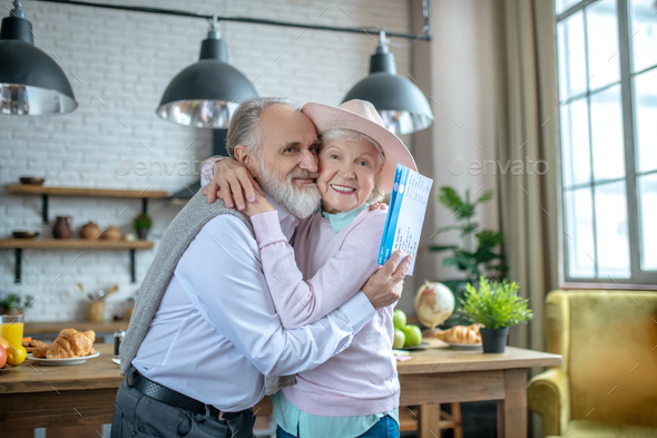 Hugging elderly couple holding their boarding passes - Stock Photo - Images