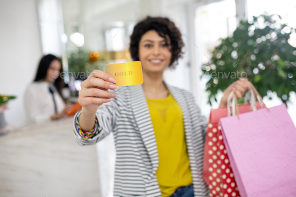 Curly-haired pretty woman holding a discount card in hands