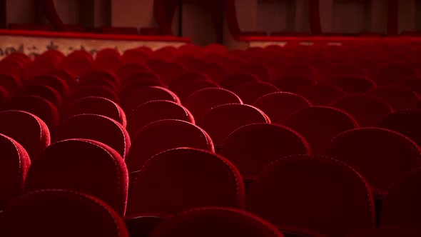 Selective focus on empty rows with red velvet seats in theater hall. Rows with empty chairs.  alt