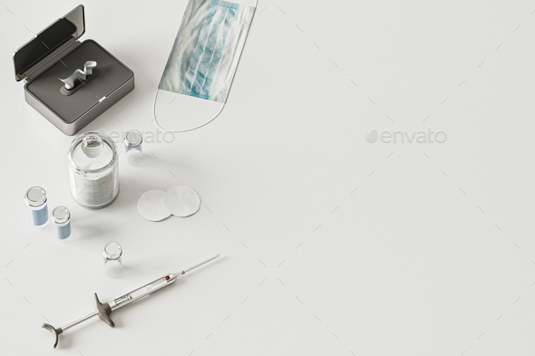 Syringe, vials, face mask on white background from above, coronavirus vaccination concept