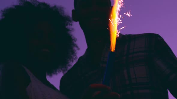 Couple holding sparklers on beach at dusk 4k