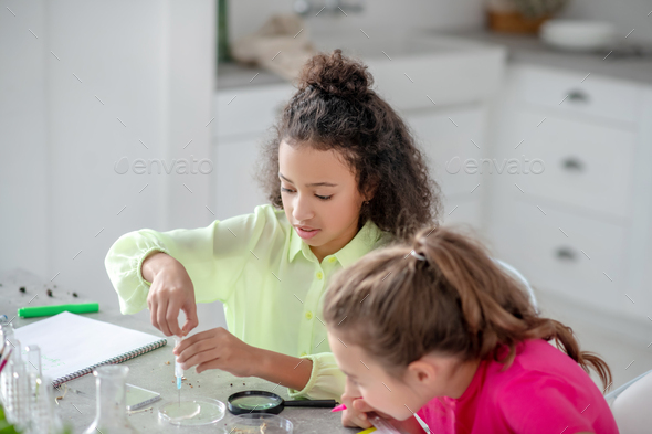 Two girls sitting at the table conducting an experiment.